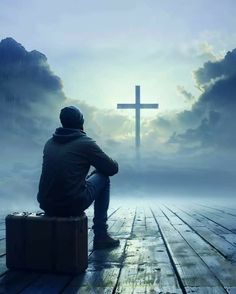 a man sitting on top of a wooden floor next to a cross in the sky