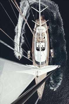 an aerial view of a sailboat in the water with its sails spinning behind it