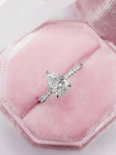 a diamond engagement ring in a pink velvet gift box with its lid open to show it's inside