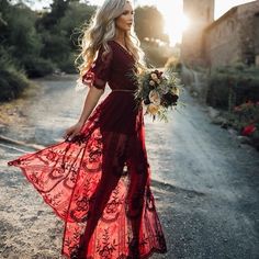 a woman in a red dress is walking down the road with her bouquet on her hand