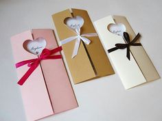 three different colored boxes with hearts and ribbons tied around the top one is pink, white, and brown