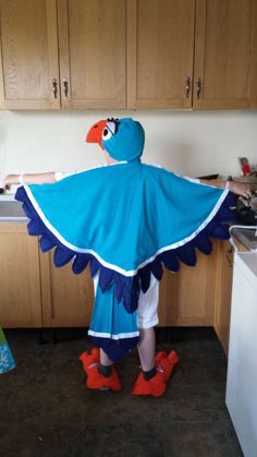 a person wearing a blue bird costume in a kitchen