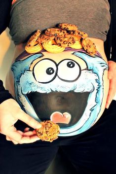 a pregnant woman holding cookies and doughnuts in her belly with an image of cookie monster on it's stomach