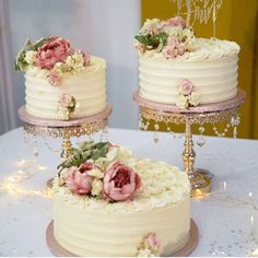 two white wedding cakes with pink flowers on each cake stand and one is decorated with crystal beads