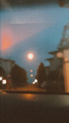 blurry photograph of street lights at night from inside the car window, taken with polaroid film