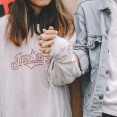 two people standing next to each other holding hands