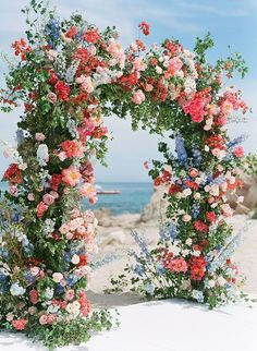 an arch made out of flowers on the beach