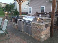 an outdoor kitchen with grill and seating area