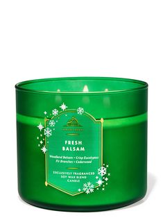 a green candle with snowflakes on the top and bottom, sitting in front of a white background