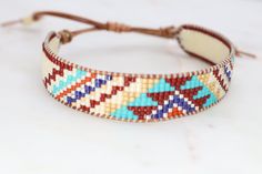 a beaded bracelet is shown on a white surface with a brown cord and beads