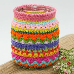 multicolored crocheted vase sitting on top of a wooden table