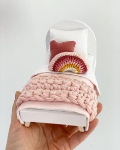 a hand holding a small crocheted pillow in it's packaging with a cushion on top