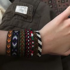 a close up of a person's hand holding a cell phone with bracelets on it