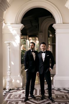 two men in tuxedos are posing for a photo outside the entrance to a building