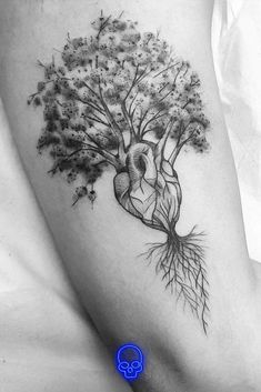 a tree with roots and a human heart tattoo on the right side of the thigh