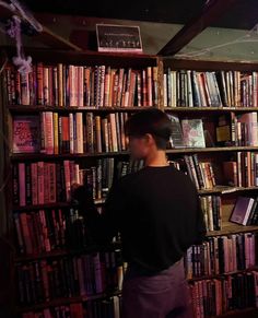 a man standing in front of a book shelf filled with books