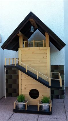 a wooden birdhouse with two plants in it's bottom tier and stairs leading up to the second floor