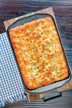 a casserole in a baking dish on a wooden table next to a blue and white checkered napkin