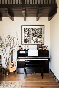 a black piano sitting in the middle of a living room next to a vase with flowers