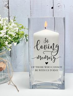 a white candle sitting on top of a table next to a vase filled with flowers