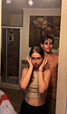 a man and woman standing in front of a mirror with their hands on their faces