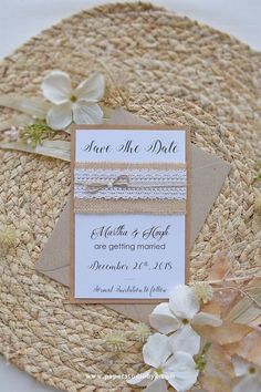 the wedding stationery is laid out on top of a straw hat with ribbon and flowers