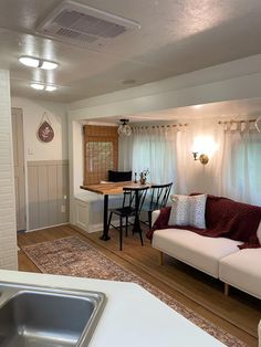 a living room filled with furniture next to a kitchen and breakfast nook area on top of a hard wood floor