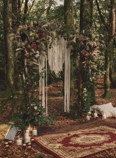 an outdoor wedding setup with candles, flowers and greenery on the ground in the woods