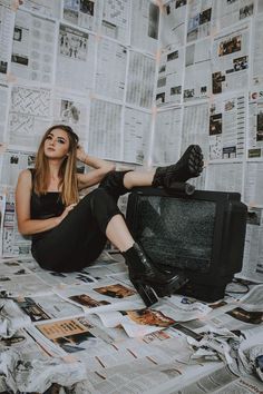 a woman sitting on top of a bed in front of a tv surrounded by newspapers