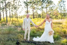 a bride and groom holding hands in the woods