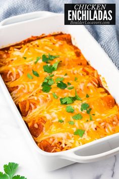 chicken enchiladas in a white casserole dish with cilantro and parsley