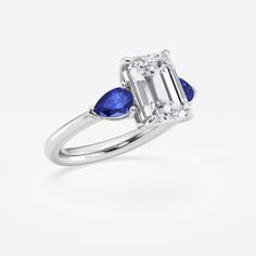 an engagement ring with two pear shaped blue sapphires on the side and a baguett cut diamond in the center