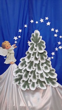 an angel standing on top of a christmas tree next to a blue background with white stars