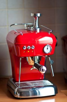 a red espresso machine sitting on top of a counter