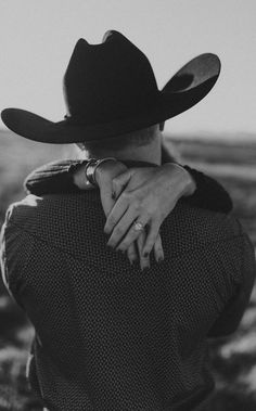 a black and white photo of a man in a cowboy hat hugging another man's back