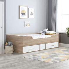 a bedroom with a bed, dresser and rug in front of a window on the floor