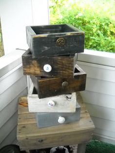 a stack of wooden boxes sitting on top of a table in front of a window