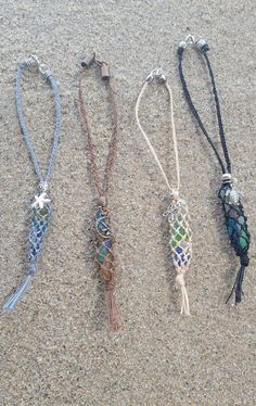 four different necklaces are laying on the sand