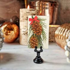 a pine cone with a red bow on it is sitting on a table next to other christmas decorations