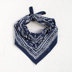 a blue bandana with white designs on it sitting on top of a white surface