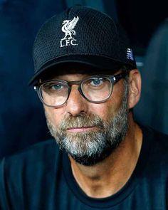 a man wearing glasses and a hat looks at the camera while sitting in front of him