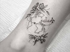 a small world map with flowers on the side of the foot tattoo by pink becker