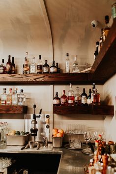 the shelves are full of liquor bottles and glasses on the bar counter in this kitchen