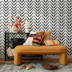 a yellow bench in front of a black and white wallpaper with geometric designs on it