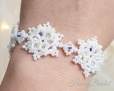 a close up of a person's arm wearing a bracelet with white beads and blue stones