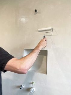 a man is painting the wall with white paint