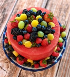 a watermelon cake topped with fresh fruit on a blue and white plate sitting on a wooden table