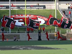 a group of people on a field with flags and banners in front of an empty bleachers