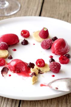 raspberry cheesecake on a white plate topped with whipped cream and fresh raspberries