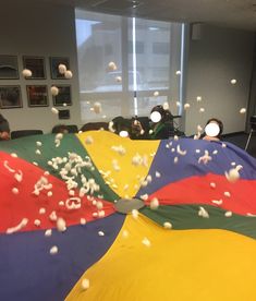 several people are sitting in an office with large umbrellas that have been blown up